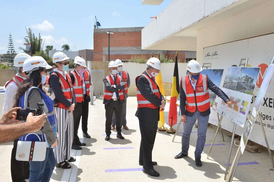 Visite de chantier : équipe en casques et gilets autour des plans